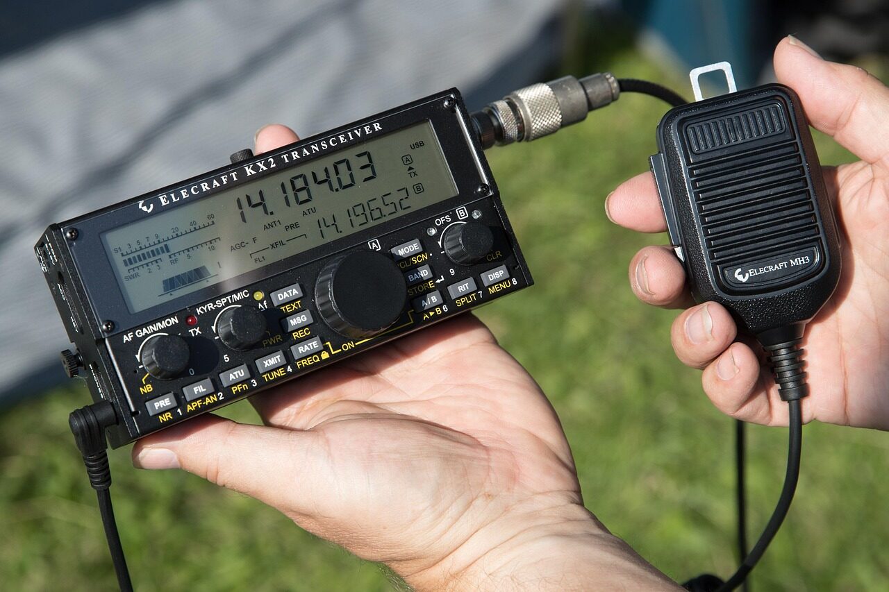 An emergency responder operating a portable HF radio set at a remote field station.