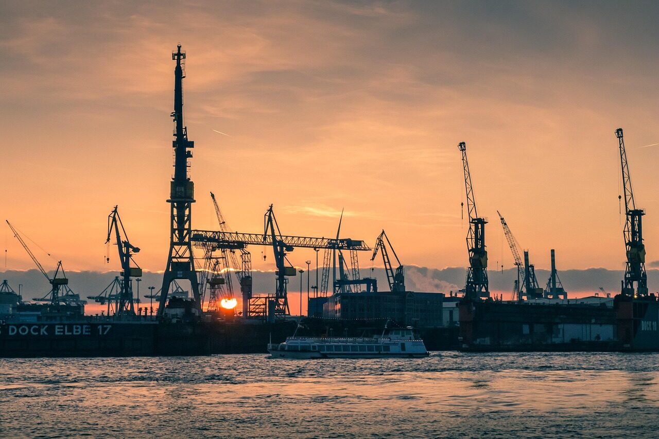 Container terminal at dawn with cargo cranes and stacked boxes awaiting movement.