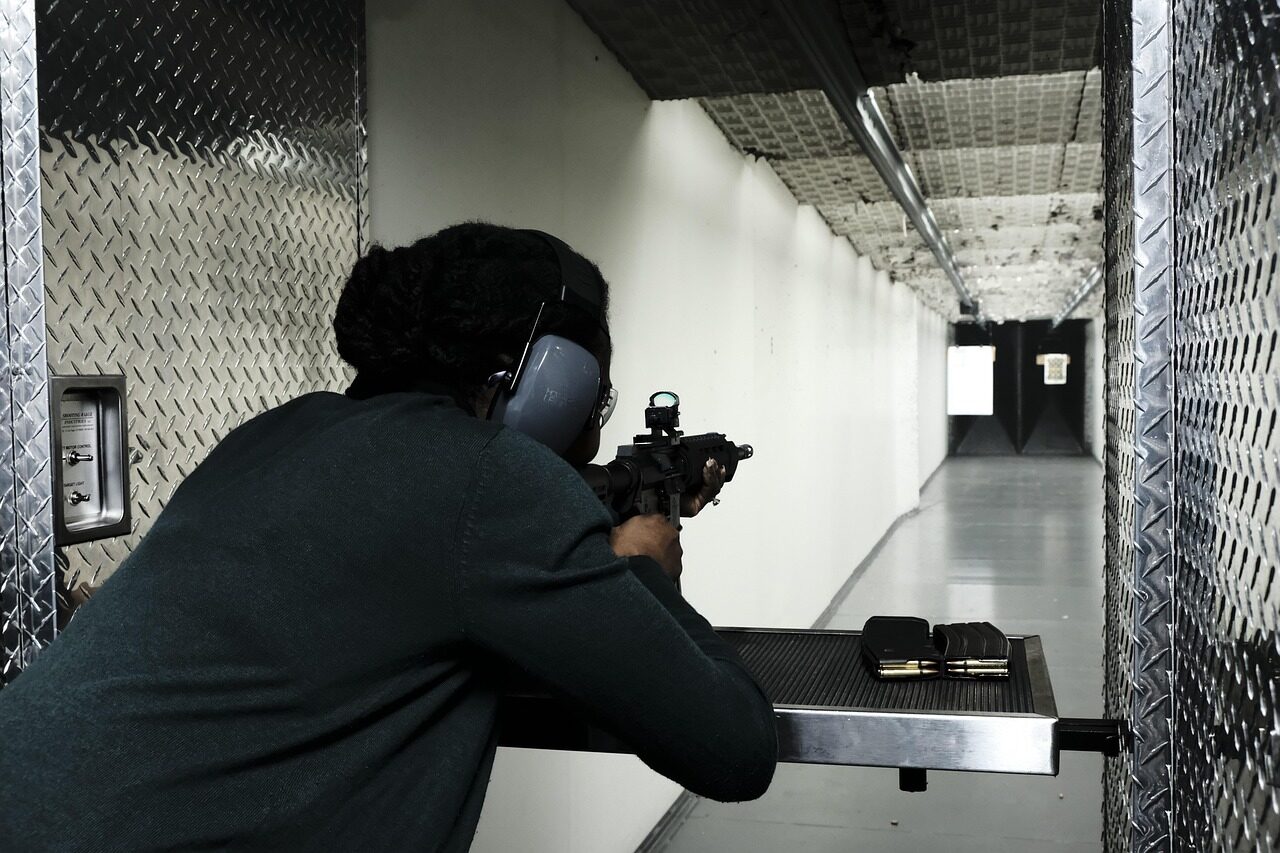 An armourer inspecting and cleaning carbine components at a maintenance bench.