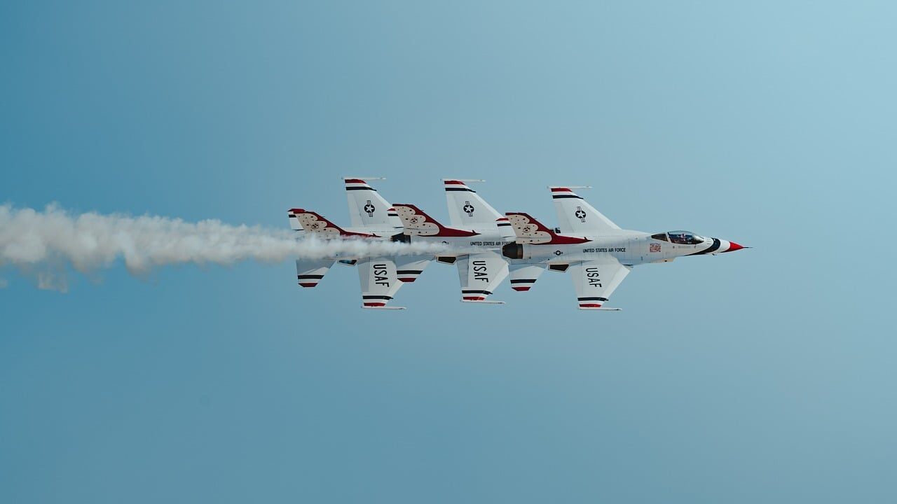 A coordinated group of small drones flying in formation above an open training field.